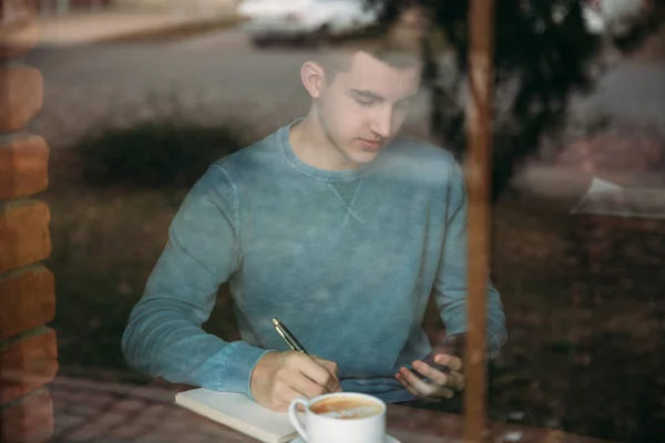Επιχείρηση άνθρωπος εργάζεται και πίνοντας καφέ σε μια καφετέρια και Γράψτε κάτι στο Σημειωματάριο — Φωτογραφία Αρχείου