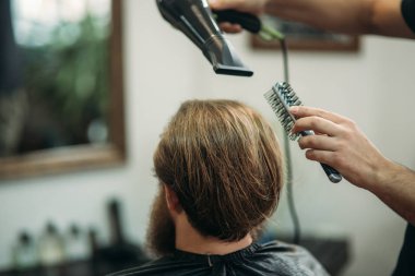 Ana saç ve sakal Berber Dükkanı'nın adamlarından keser ve bir saç kurutma makinesi kullanır