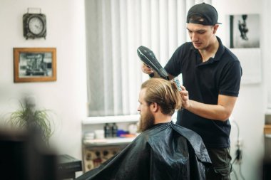 Ana saç ve sakal Berber Dükkanı'nın adamlarından keser ve bir saç kurutma makinesi kullanır