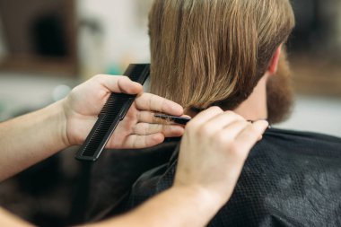 Sakallı adam saçını tarak kullanarak ve makas damat bir profesyonel Kuaför tarafından elde. Closeup görünümü ile sığ derinlik-in tarla