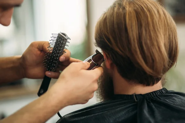Hombre barbudo con un corte de pelo con una cortadora de pelo — Foto de Stock