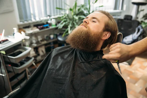 handsome young bearded guy sitting in an armchair in a beauty salon