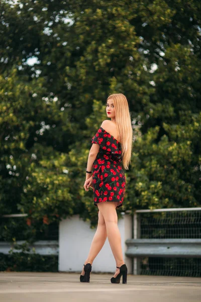 Blond flicka i röd klänning poserar för fotografen — Stockfoto