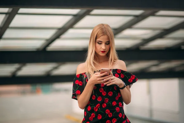 Blond meisje met behulp van telefoon en glimlachen — Stockfoto