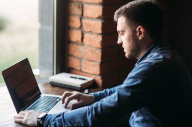 Bir sakallı bir dizüstü bilgisayar bir kafede kullanır.