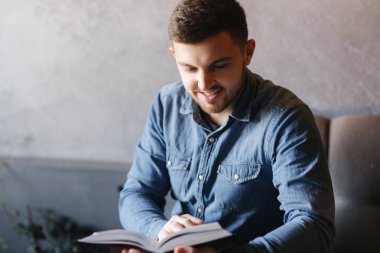 Bir kafede bir kitap okuma sakallı yakışıklı adam