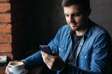 Telefonunuzun içinde bir restoran ve bir kahve yudumlarken denim gömlekli sakallı adam