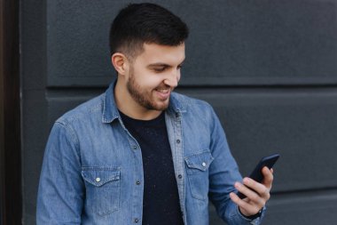 Yakışıklı bir kot gömlek bir telefon ayakta sokakta kullanır.