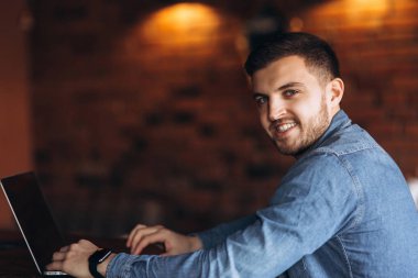 Bir sakallı bir dizüstü bilgisayar bir kafede kullanır.