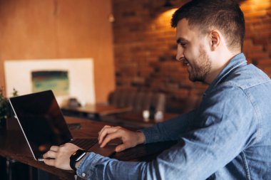 Bir sakallı bir dizüstü bilgisayar bir kafede kullanır.