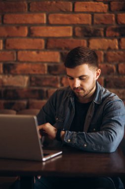 Bir sakallı bir dizüstü bilgisayar bir kafede kullanır.