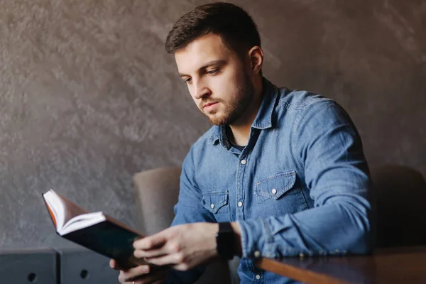 Knappe man met een baard die lezen van een boek in een café — Stockfoto