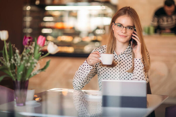 beautiful blond lady use different gadgets and drinking coffee in cafe