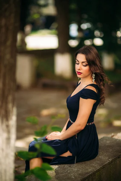 Une belle fille en robe bleue se promène dans le parc . — Photo