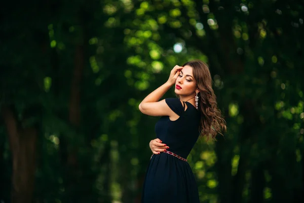 Een mooi meisje in een blauwe jurk is wandelen in het park. — Stockfoto