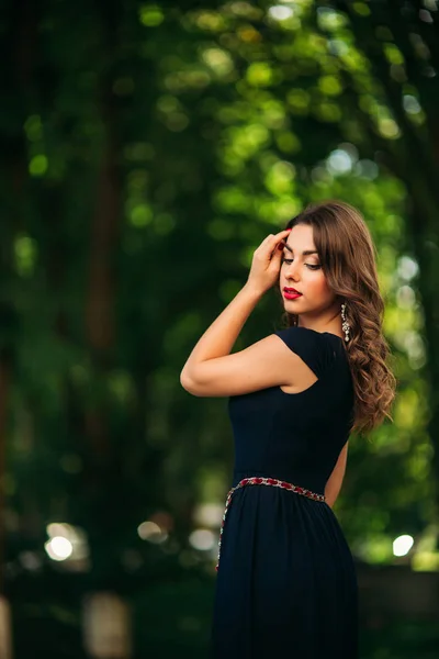 Una hermosa chica en un vestido azul está caminando en el parque . — Foto de Stock