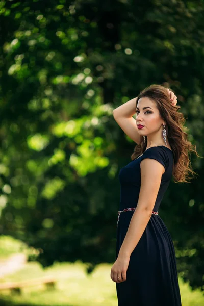 Una bella ragazza con un vestito blu cammina nel parco . — Foto Stock