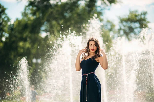 Uma menina está andando pela cidade, perto de uma grande fonte . — Fotografia de Stock