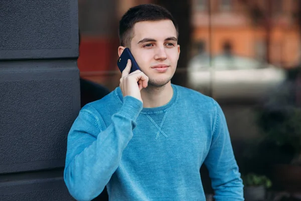 Un bel homme utilise le téléphone dans la rue. — Photo
