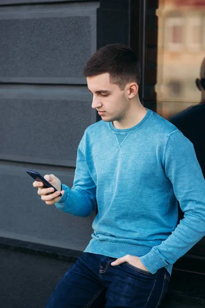 Un bel homme utilise le téléphone dans la rue. — Photo