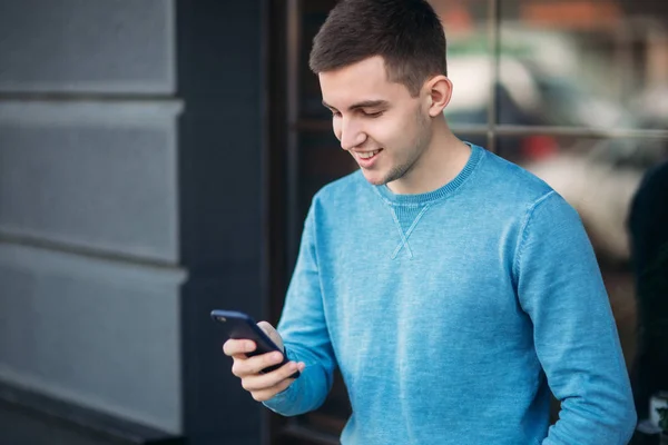 Handsome man is using the phone on the street — Stock Photo, Image