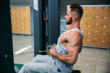 Genç bir atlet spor salonunda eğitiyor. Sırt ve göğüs kaslarının gösterir