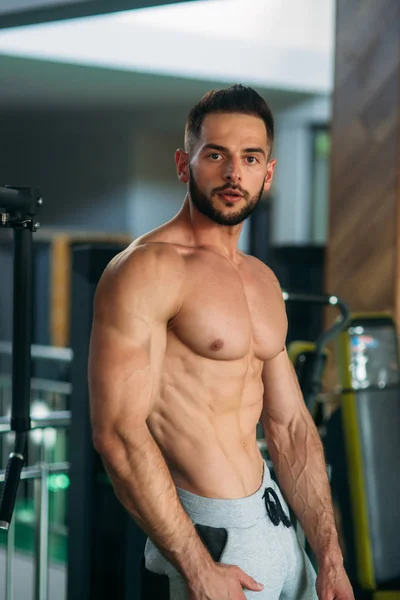 A young athlete trains in the gym. Shows the muscles — Stock Photo, Image