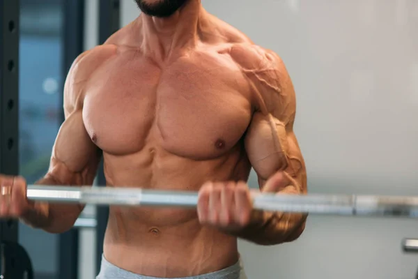 Un joven atleta entrena en el gimnasio. Trians bíceps musculares —  Fotos de Stock