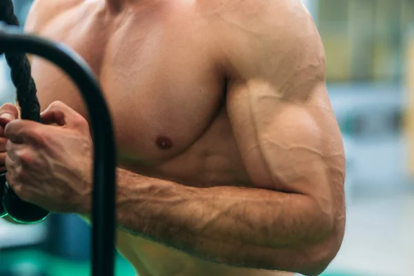 Um jovem atleta treina no ginásio. Fisiculturista treina os músculos do tríceps — Fotografia de Stock