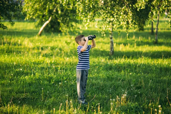 Niño con una camiseta a rayas mira a través de los prismáticos. —  Fotos de Stock