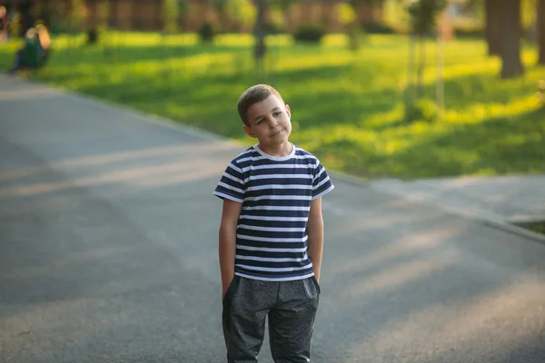 Ein kleiner Junge im gestreiften T-Shirt spielt auf dem Spielplatz, schaukelt auf einer Schaukel — Stockfoto