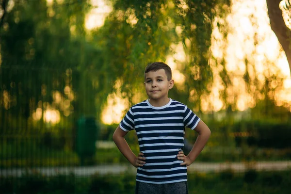 緑の背景の前にストライプ t シャツ立っての少年。笑顔でカメラマンを探して. — ストック写真