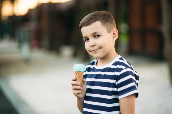 Маленький мальчик в полосатой футболке ест синее мороженое. — стоковое фото