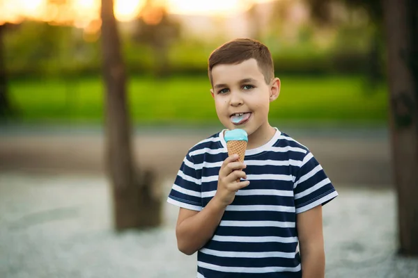 Egy kis fiú a csíkos póló kék fagylalt eszik. Tavasz, napsütés — Stock Fotó