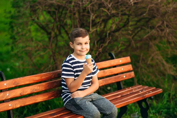 ストライプ t シャツを着た小さな男の子は、ブルーのアイス クリームを食べています。春には、日当たりの良い天気 — ストック写真