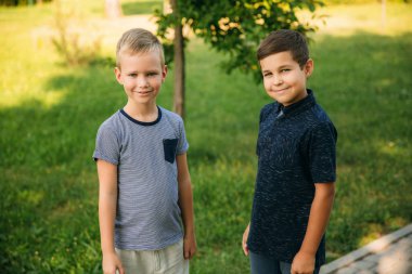 Çocuklar parkta oynuyorlar. İki güzel çocuk T-shirt ve şort gülümseyen eğlenin. Dondurma yemek, sıçrama, çalıştırın. Yaz güneşli