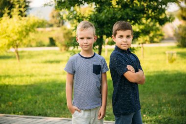 Çocuklar parkta oynuyorlar. İki güzel çocuk T-shirt ve şort gülümseyen eğlenin. Dondurma yemek, sıçrama, çalıştırın. Yaz güneşli