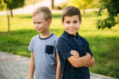 Çocuklar parkta oynuyorlar. İki güzel çocuk T-shirt ve şort gülümseyen eğlenin. Dondurma yemek, sıçrama, çalıştırın. Yaz güneşli