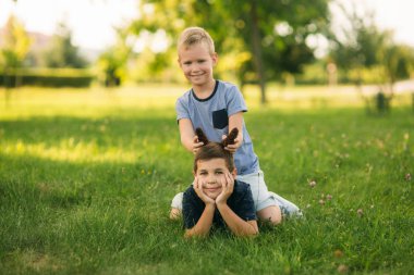 Çocuklar parkta oynuyorlar. İki güzel çocuk T-shirt ve şort gülümseyen eğlenin. Dondurma yemek, sıçrama, çalıştırın. Yaz güneşli