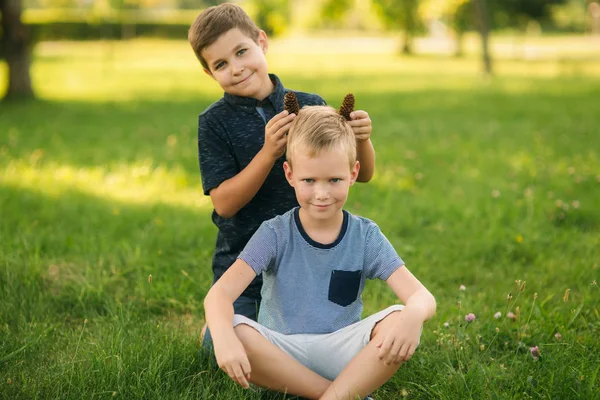 Two children are playing in the park. Two beautiful boys in T-shirts and shorts have fun smiling. They eat ice cream, jump, run. Summer is sunny