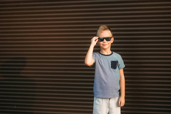 Chico guapo sonriendo y posando para el fotógrafo. Un niño alegre camina por el parque. Tiempo soleado verano . — Foto de Stock