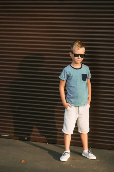 Stilig pojke ler och poserar för fotografen. Glada barn promenader i parken. Soligt väder sommar. — Stockfoto