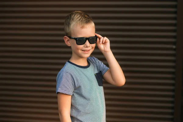 Beau garçon souriant et posant au photographe. Joyeux enfant marche dans le parc. Météo ensoleillée été . — Photo