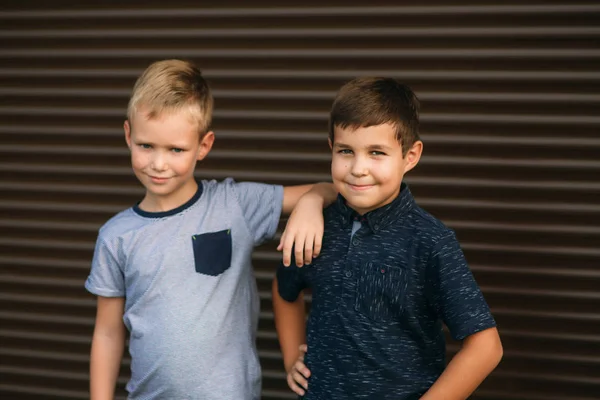 Zwei Kinder spielen im Park. Zwei schöne Jungs in T-Shirts und Shorts haben Spaß beim Lächeln. Sie essen Eis, springen, rennen. Sommer ist sonnig — Stockfoto