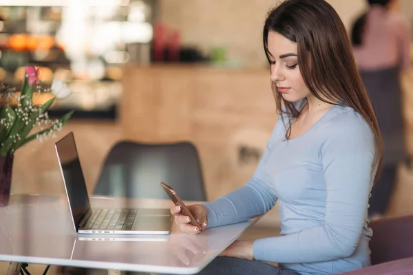 Mooie brunette vrouw gebruik bedrijfstelefoon in een café met laptop — Stockfoto