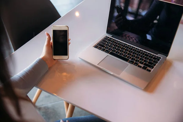 Деловая леди сидит в кафе, работает на ноутбуке и пользуется телефоном — стоковое фото