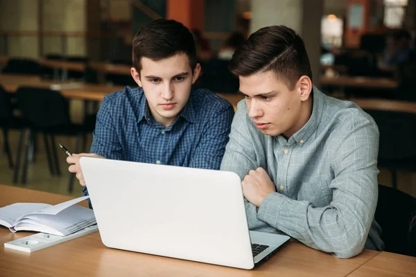Два школьника пользуются ноутбуком в библиотеке — стоковое фото