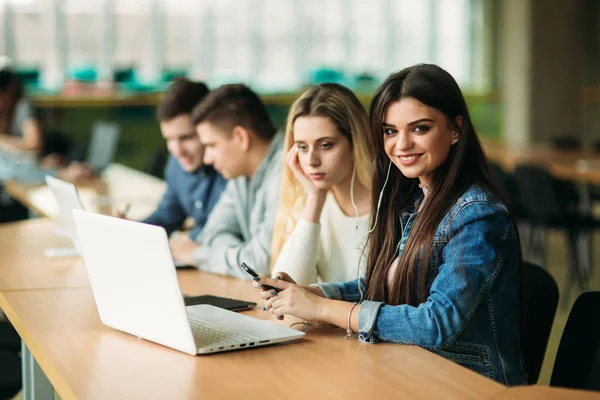 Ομάδα από φοιτητές που σπουδάζουν στη βιβλιοθήκη του σχολείου, ένα κορίτσι και ένα αγόρι είναι χρησιμοποιώντας ένα φορητό υπολογιστή και σύνδεση στο internet — Φωτογραφία Αρχείου