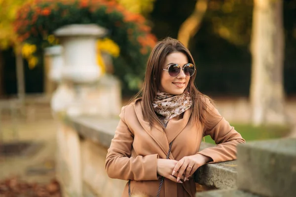 Stylowa dziewczyna w brązowy płaszcz, szalik z okularami. Używanie telefonu w Paryżu Francja. Makijaż — Zdjęcie stockowe