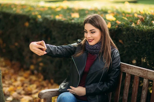 Snygg vacker dam i en svart skinnjacka med en svart påse och brun päls, makin selfie — Stockfoto